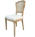 Angled view of Lilian weathered oak dining chair showing oatmeal linen seat, rattan back and turned timber legs.