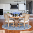 Lilian Rattan Dining Chairs in weathered oak styled around a timber dining table with blue rug and hydrangeas in a Hamptons dining room.