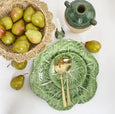 Lucy rattan scallop bowl filled with green pears, styled with green cabbage plates, gold cutlery and rustic ceramic accents
