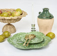 Lucy rattan scallop bowl filled with green pears, styled with green cabbage plates, gold cutlery and rustic ceramic accents