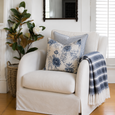Coastal living room corner featuring Magnolia Tree Green 115cm in woven basket beside a white slipcover armchair styled with blue floral cushions and striped throw