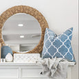 Malibu Ocean Cushion styled on a white console with rattan mirror and coastal Hamptons decor