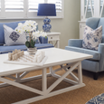 Coastal Hamptons living room with blue armchairs, white coffee table, marble chess set, orchid arrangement, and blue patterned table lamp