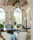 coastal living room with arched windows, blue striped sofa and timber beams from Beautiful by Mark D Sikes