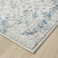 Marlowe Porcelain Rug corner showing the distressed blue and grey pattern against its warm ivory ground.