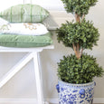 olive embroidered cushion layered with green cushions on white bench beside potted topiary