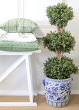 olive embroidered cushion layered with green cushions on white bench beside potted topiary