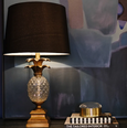 antique gold pineapple lamp with black shade styled on console with books