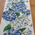 blue hydrangea outdoor table runner in durable polyester fabric, coastal Hamptons style table linen for indoor and outdoor dining. Close up of pattern.