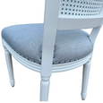 Close-up of the Olivia White Dining Chair showing the duck egg linen seat, antique stud detailing and handwoven rattan back.