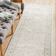 Parker Winter White Runner Rug styled in a hallway beside a tufted bench with a soft vintage-inspired pattern.