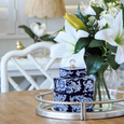 Peony Canister with Lid 20cm styled on a silver tray beside white lilies and greenery in a glass vase, creating an elegant blue and white Hamptons-inspired dining table display.
