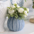 Peony Fittonia Mix Bouquet White displayed in a blue decorative vase on a coastal-style console table with artwork backdrop