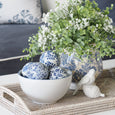 Paume Whitewash Rattan Rectangle Tray styled with blue and white ceramic decor balls, botanical vase and greenery.