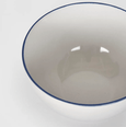 Top view of white stoneware bowl with soft blue-grey rim