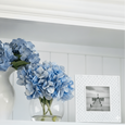 blue hydrangea in glass sphere vase styled on white shelf with ceramic vase and photo frame, elegant coastal home decor in Hamptons style interior