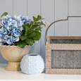 Ripple Tin Basket with Handle styled beside blue hydrangea arrangement and white ceramic décor on coastal console table