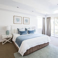 Coastal bedroom featuring ocean blue velvet throw at foot of bed with soft blue accents and neutral tones
