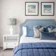 Rodeo Ocean blue velvet cushions styled on a Hamptons bedroom with layered blue cushions and throw
