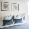 Rodeo Ocean Rectangle Cushions styled on a white Hamptons bed with layered blue and white cushions and coastal artwork.