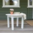 Round Adirondack Side Table White 70cm styled on a covered verandah with books and flowers
