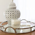 Close-up of mirrored tray with candle and decorative ceramic jar