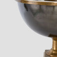 Detail of antique brass footed ice bucket showing the dark metal bowl, brass rim and raised pedestal base.