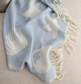 close-up of blue and white shell jacquard throw with soft fringe detailing on neutral sofa
