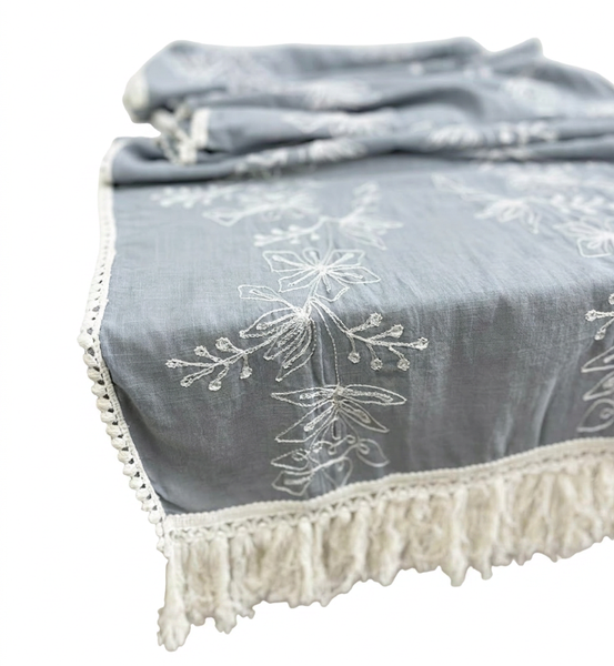 Blue embroidered table runner with white botanical pattern and fringe detail