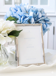 Silver bamboo photo frame styled with blue hydrangeas on white tray
