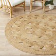 Natural jute round rug styled with rattan chair in a coastal living space