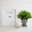 Verdant Urn Faux Topiary styled on a shelf beside a bone photo frame and decorative bird ornament in a Hamptons interior