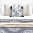 Vintage Paisley Grey and White Bedspread layered on a white bed with neutral striped and blue and white cushions in a Hamptons bedroom.