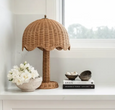 Rattan table lamp styled on console with books and white flowers coastal interior
