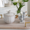 White ceramic bird canister with decorative duck ornament styled on a timber tray beside white faux florals in a glass vase for soft coastal home décor