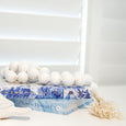 White wooden hanging beads styled on stacked books beside blue-and-white coastal home decor.