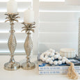 White wooden hanging beads styled on books beside silver candle holders and coastal decor.