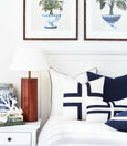 Navy cushion with white piping styled on a Hamptons bed with layered white and patterned cushions