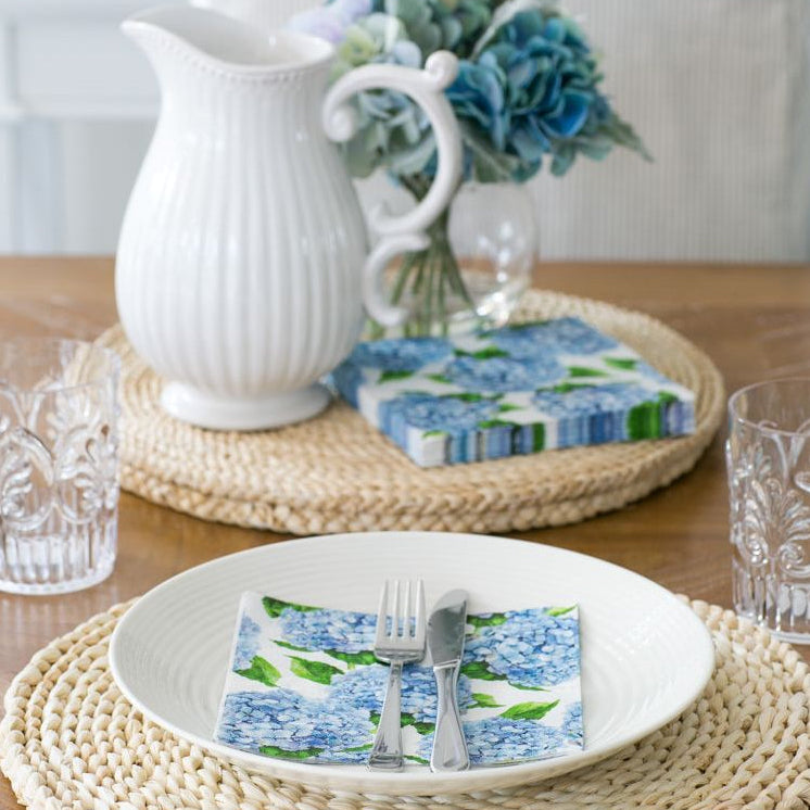blue hydrangea lunch napkins styled on white plate with rattan placemat in coastal table setting