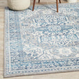 Bridgeport Blue rug styled under a light-coloured sofa, showing textured blue and ivory pattern in a coastal living space