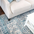 Bridgeport Blue rug styled under a light-coloured sofa, showing textured blue and ivory pattern in a coastal living space