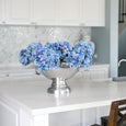 Blue hydrangea bundle styled in a silver bowl on a white kitchen island in a Hamptons style home