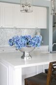 Blue hydrangea bundle styled in a silver bowl on a white kitchen island in a Hamptons style home