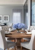 Blue hydrangea bundle styled in a glass bowl on a round dining table in a Hamptons style home