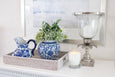 Blue and white lotus flower ginger jar styled on a rattan tray with coordinating blue and white ceramics in a Hamptons-style interior