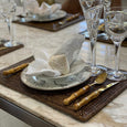 Rattan rectangular placemat styled on a dining table with plates, glassware and bamboo cutlery